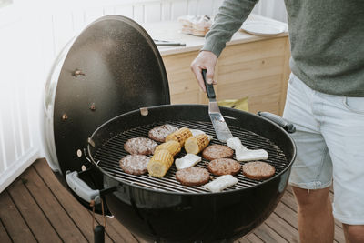 Close-up of man preparing meat on grill