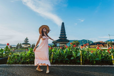 Woman standing at pura ulu danau temple against sky during sunrise