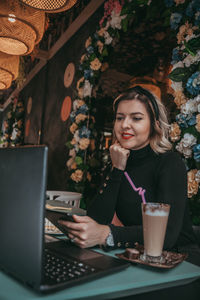 Portrait of young woman using smart phone at table