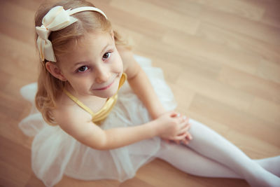 Portrait of smiling girl sitting on hardwood floor