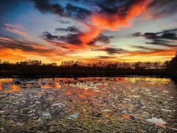 Scenic view of lake against dramatic sky during sunset