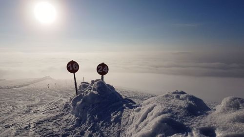 View of signs on snow covered landscape against sky during sunset