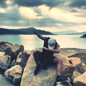 Full length of man on rocks at beach against sky