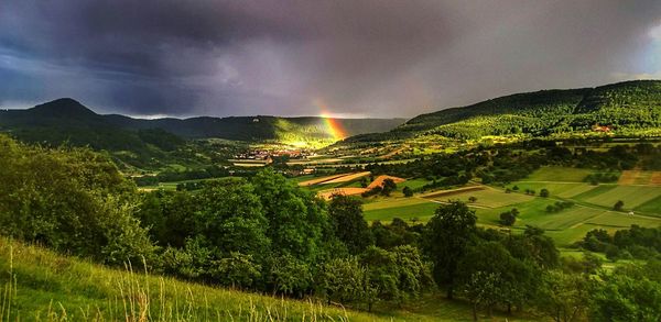 Scenic view of landscape against rainbow in sky