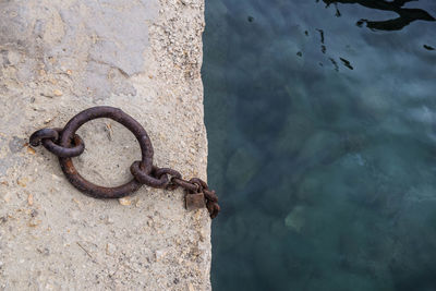 Overhead view of mooring chains on concrete dock against blue sea.