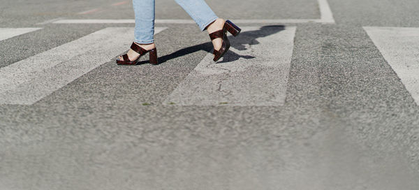 Low section of woman walking on road