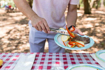 Midsection of man talking food in plate