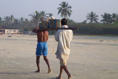 Rear view of men carrying baskets at beach 