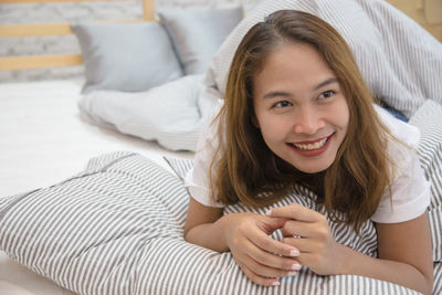 Portrait of smiling young woman lying on sofa