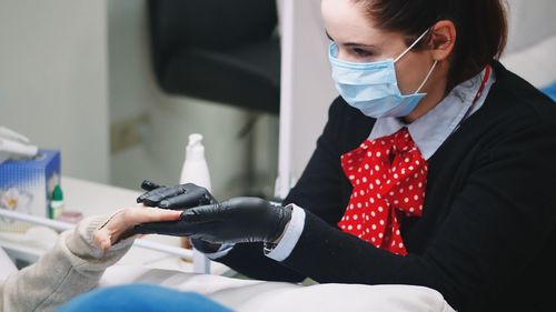 Close-up of salon artist holding customer hands