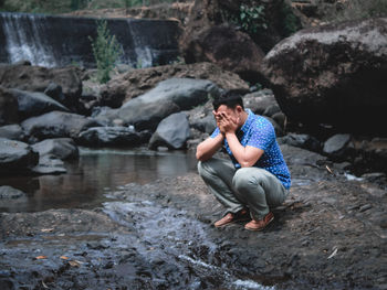 Young man sitting on rock