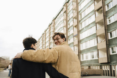 Smiling man looking over shoulder while walking with male friend