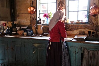 Rear view of woman cooking food in old kitchen at home