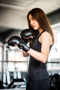 Low angle view of confident young woman practicing boxing in gym