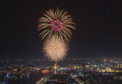 Firework display in city against sky at night