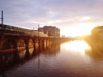 Bridge over calm river at sunset