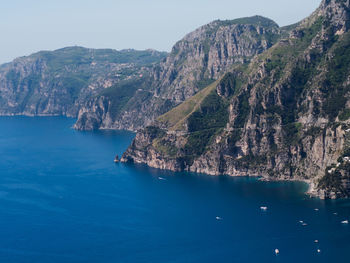 Scenic view of sea by mountains against clear sky