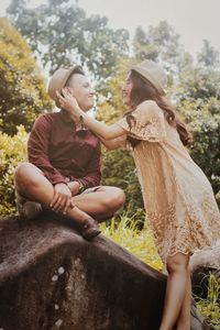 Low angle view of couple romancing against trees in forest