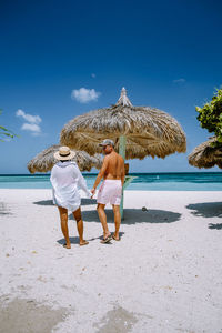 Rear view of friends on beach against sky