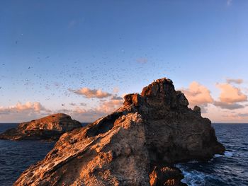 Scenic view of rock formation in sea against sky