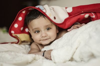 Portrait of cute baby boy lying on bed at home