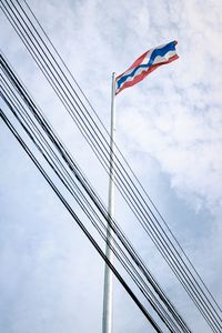 Low angle view of flag and cables against sky