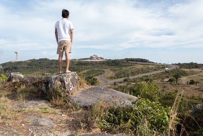 Full length of man standing on rock against sky