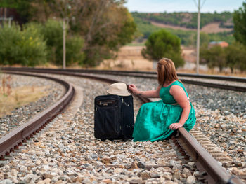 Woman with bag sitting on railroad track