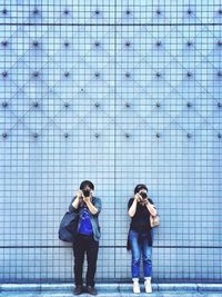 Full length of people photographing against wall