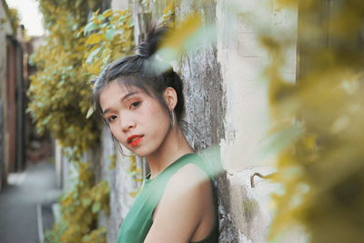 Portrait of young woman standing against wall