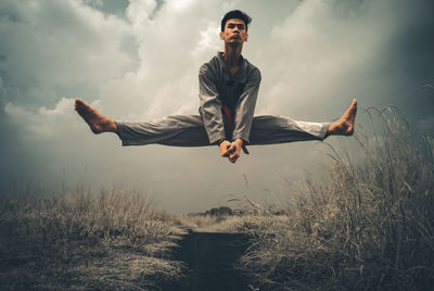 Portrait of young man flying over field against sky