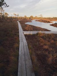 View of boardwalk leading towards landscape against sky