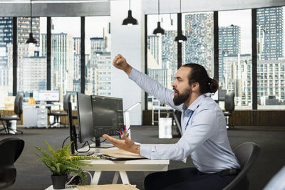 Side view of man using mobile phone in office