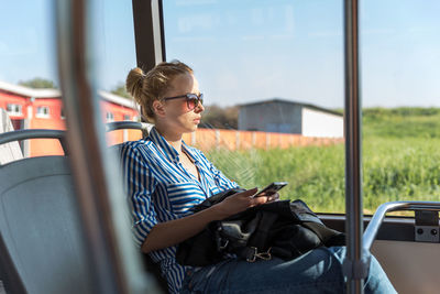 Beautiful woman using smart phone while sitting in bus