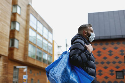 Low angle view of young man looking away in city