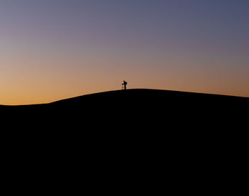 Silhouette person standing on shore against sky during sunset