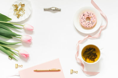 Spring flat lay with a bouquet of pink tulips. a woman's workplace. tea break with donat
