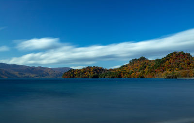 Scenic view of sea and mountains against blue sky