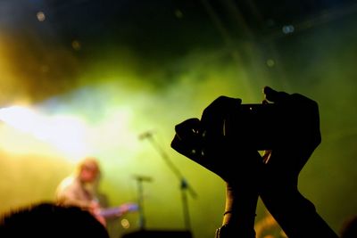 Cropped hands of person holding camera in concert