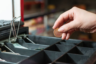 Close-up detail of latin woman's hand taking money from the cash register, making a sale 