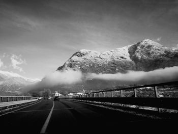 Road by mountains against sky