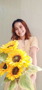 Portrait of smiling young woman against white wall