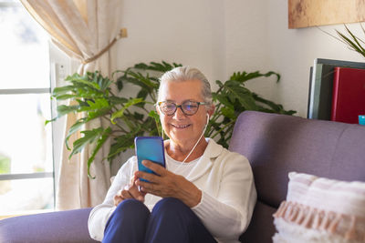 Smiling senior woman video calling while sitting at home