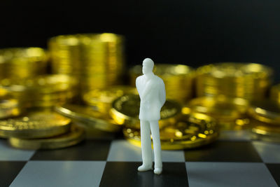 Close-up of figurine and coins on chess board