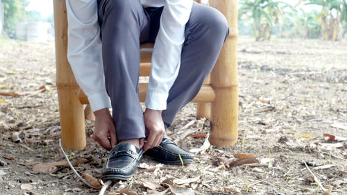 Low section of man wearing shoes while sitting on land