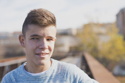 Thoughtful teenage boy standing on footbridge in city