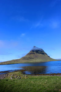 Scenic view of sea and mountains against blue sky. kirkjufell