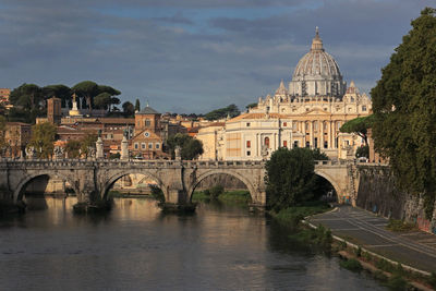 Arch bridge over river against buildings in city