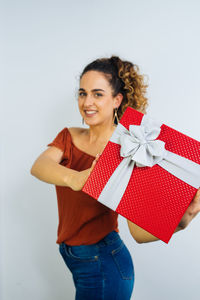 Portrait of smiling woman holding gift against white background