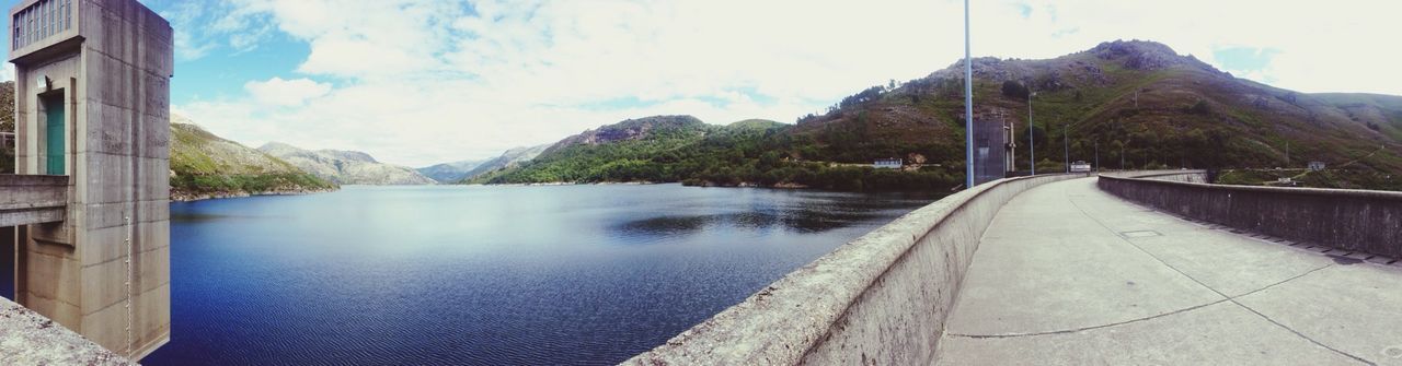 mountain, sky, water, built structure, architecture, the way forward, building exterior, tranquility, mountain range, tranquil scene, scenics, nature, lake, beauty in nature, cloud - sky, river, day, reflection, house, diminishing perspective